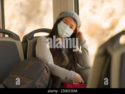 Lifestyle-Porträt der jungen attraktiven und hübschen asiatischen Frau tragen Maske im Eisenbahnwaggon, der in neuer normaler Viruszeit unterwegs ist - Süße japanische Mädchen von trai Stockfoto