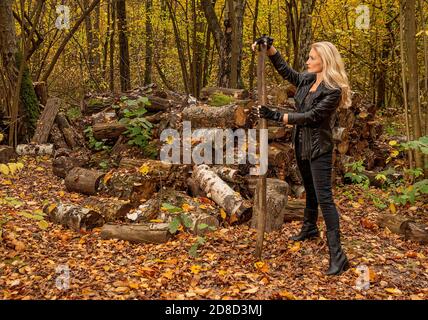 Im Wald steht ein Mädchen in einer Lederjacke und schwarzen Jeans. Lächelnd freundlich aussehendes Vergleichskonzept Stockfoto