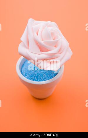 Nahaufnahme der künstlichen dekorativen rosa Rose in einem Topf Auf der orangefarbenen Oberfläche Stockfoto
