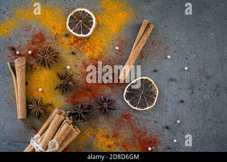 Verschiedene Gewürze auf einem Tisch. Foto von oben von Zimt, Curcuma, Zitrone, Anis und Paprika. Grauer Hintergrund mit Kopierbereich. Stockfoto