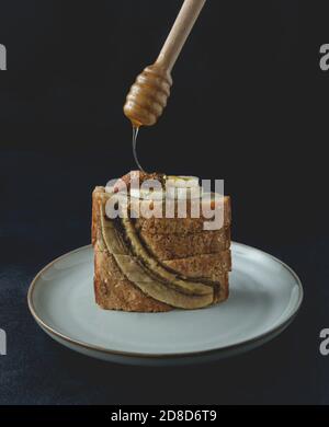 Scheiben Bananennussbrot Brot mit Honig auf dem Teller platziert. Eine appetitliche, weiche Brotstruktur, mit zerstoßenem Nuss- und Honigaroma. Vorderansicht. Stockfoto