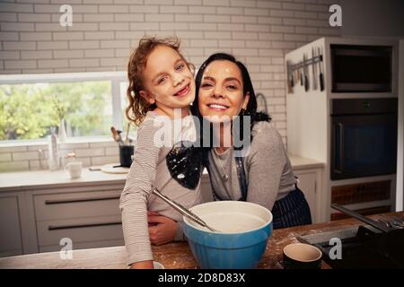 Portrait der fröhlichen Mutter und Tochter Umarmung in der Küche an Zu Hause Stockfoto
