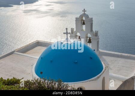 Fira, Thira, Santorini Island, Griechenland - 18. September 2020: Übernahme der katholischen Kirche der Seligen Jungfrau Maria, drei Glocken. Blick auf den Sonnenuntergang Stockfoto