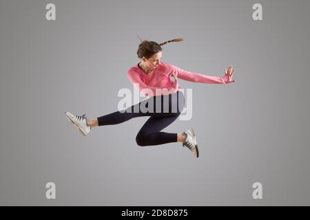 Portrait einer modernen Tänzerin, die in der Luft springt Grauer Hintergrund Stockfoto