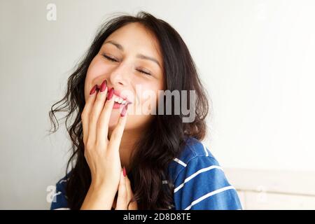 Nahaufnahme Porträt der lachenden Frau mit Hand zu Mund Und die Augen geschlossen Stockfoto