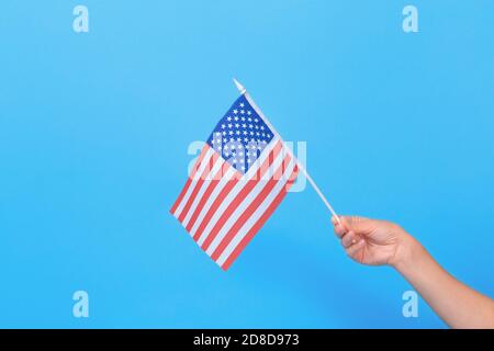 Frau Hand hält kleine amerikanische Flagge auf blauem Hintergrund. Leerzeichen für Text. Stockfoto
