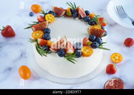 Draufsicht auf hausgemachten Vanillegeburtstorte mit Beeren verziert: Erdbeeren, Blaubeeren, Feigen auf Marmorboden. Feier, Party Kuchen. Kuchen Stockfoto