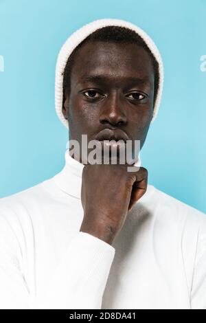 Bild von jungen ernsthaften afroamerikanischen Kerl in weißen Kleidern Blick auf die Kamera isoliert auf blauem Hintergrund Stockfoto