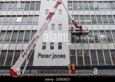 London, Großbritannien. 29. Oktober 2020. Arbeiter installieren Weihnachtsbeleuchtung an der Außenseite des Peter Jones Kaufhauses in Sloane Square. Das Geschäft ist Teil der John Lewis-Gruppe, deren Flagship-Store in der Oxford Street die Erlaubnis erhalten hat, die Hälfte des Gebäudes in Büros umzuwandeln, da das Unternehmen einen Umstrukturierungsplan durchläuft, um einen Rückgang der Geschäftsleistung während der laufenden Coronavirus-Pandemie einzudämmen. Darüber hinaus wird den Mitarbeitern erstmals seit 1953 kein jährlicher Bonus gezahlt. Kredit: Stephen Chung / Alamy Live Nachrichten Stockfoto