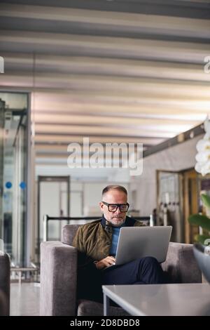 Fokussierter Mann in Brillen mit seinem Gadget Stockfoto