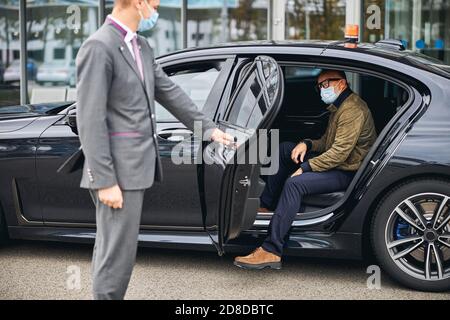 Mann in der Brille, der aus dem Elite-Taxi aussteigen kann Stockfoto