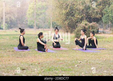 Gruppe von asiatischen Frauen mit Ruhe nach Praktiken Yoga. Frauen sitzen und reden im Outdoor-Park. Stockfoto