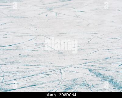 Natürlich gefrorene Eishockey Eisbahn Oberflächenstruktur mit Schlittschuh-Trails, abstrakter Hintergrund aus blauem Eis und weißem Schnee, selektiver Fokus Stockfoto