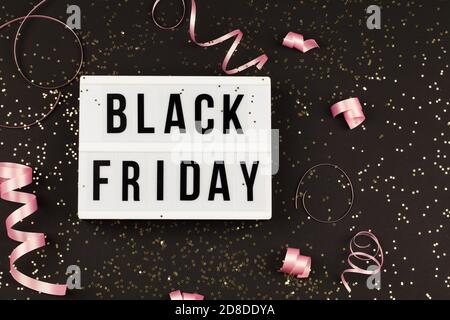 Black friday Sale Text auf weißem Leuchtkasten, goldenen Sternen und Weihnachtsband um auf schwarzem Hintergrund. Vorlage Herbst Danksagung Förderung Werbung Stockfoto
