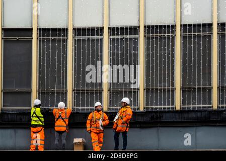 London, Großbritannien. Okt. 2020. Arbeiter hängen die Lichterketten auf - Peter Jones, Teil der John Lewis Partnership, bereitet sich auf Weihnachten vor, da die Einschränkungen des Coronavirus wieder zunehmen. Traditionelle Lichter hängen an der Fassade und Fensterdarstellungen beziehen sich meist auf Weihnachten. Kredit: Guy Bell/Alamy Live Nachrichten Stockfoto