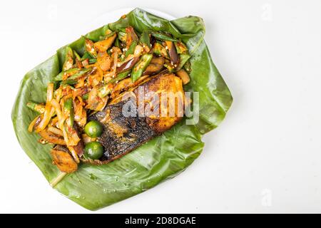 Blick von oben auf beliebten gegrillten Stachelrochen Fisch mit Gewürzen und Gemüse auf Bananenblatt serviert Stockfoto