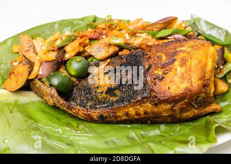 Nahaufnahme des beliebten gegrillten Stachelrochen mit Gewürzen und Gemüse Serviert auf Bananenblatt Stockfoto