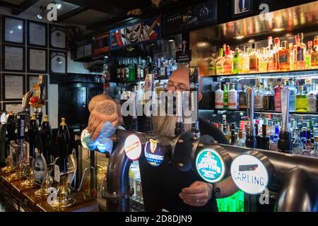 Vermieter Jay Weston putzt die Bar im Ye Olde Salutation Inn in Nottingham, bevor er seine Türen schließt, wenn am Freitag ab 0001 Uhr Tier-3-Beschränkungen in Kraft treten. Stockfoto