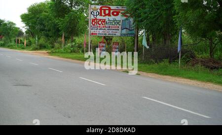 22. September 2020 : Mahroli, Rajasthan, Indien / leere Straße und Reklamebrett. Blick auf leere rote Straße am Morgen mit blauem Himmel oben. Stockfoto