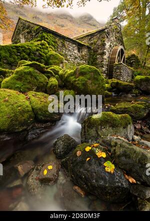 Alte ausgediente Wassermühle mit kleinem Wasserfall und wunderschönen Herbstfarben/Moos auf Felsen. Aufgenommen in Borrowdale, Keswick, Lake District, Großbritannien. Stockfoto