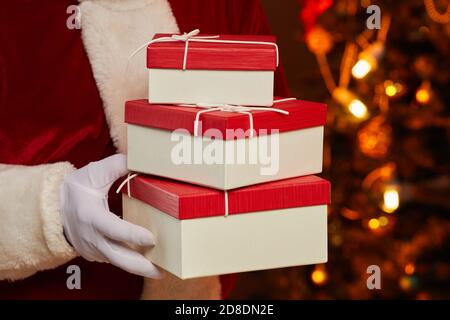 Nahaufnahme des Weihnachtsmannes in Handschuhen, die Stapel von Geschenkschachteln tragen In seinen Händen Stockfoto