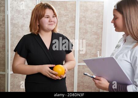 Arzt Ernährungsberaterin, Ernährungsberaterin und Patientin auf Konsultation im Büro. Junge lächelnde Ernährungsberaterin im Sprechzimmer Stockfoto