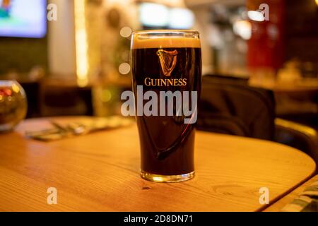 DUBLIN, IRLAND - Januar. 9, 2020: Ein Glas guinness dunkles Bier mit Schaumstoff steht auf einem Holztisch in einer Bar. Beliebtes irisches Bier. Stockfoto