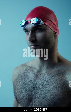 Nahaufnahme professionelle kaukasischen männlichen Schwimmer Vorbereitung für das Training isoliert auf blau neoned Studio Hintergrund. Anmut von Bewegung und Aktion. Gesundes Lifestyle-, Sport- und Bewegungskonzept. Stockfoto