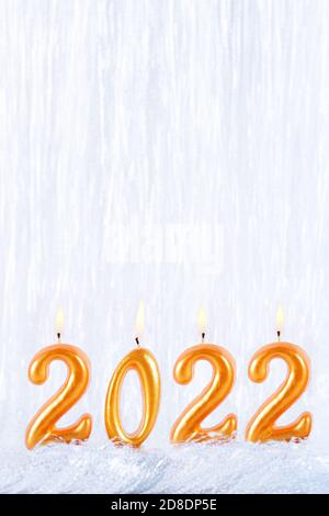 Vier goldene Kerzen schreiben Zahlen Flamme. Frohes neues Jahr 2022 Stockfoto