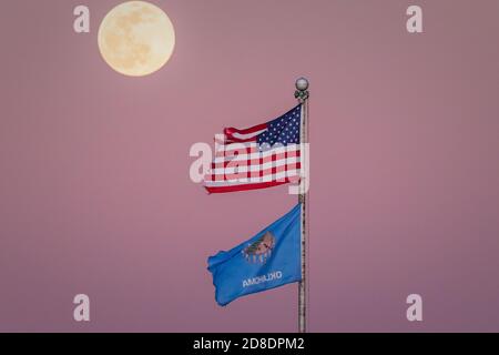 Ein schöner Vollmond, der über die amerikanische und Oklahoma Flag steigt, während die Sonne untergeht. Stockfoto