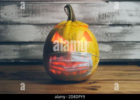 Düstere Jack-o-Laterne in einer medizinischen Maske auf einem hölzernen Hintergrund Stockfoto