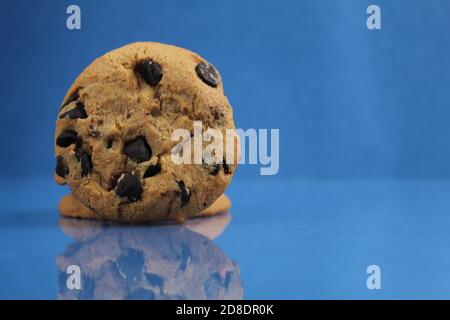 Food Background Cookies rund mit Schokolade Tropfen liegend auf Die Kante der Kante mit einer Reflexion auf einem Blau reich hell Spiegel Hintergrund si Stockfoto