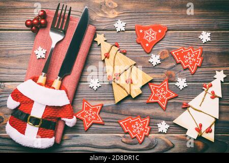 Blick von oben auf die Gabel und Messer, mit Band gebunden auf Serviette auf Holz- Hintergrund. Nahaufnahme von Weihnachtsschmuck und Tannenbaum. Happy Holiday conc Stockfoto