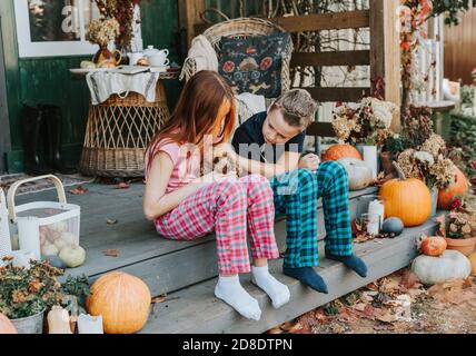 Kinder ein Junge und ein Mädchen im Pyjama mit ihren Hund, der Spaß auf der Veranda des Hinterhofs eingerichtet Mit Kürbissen im Herbst Stockfoto