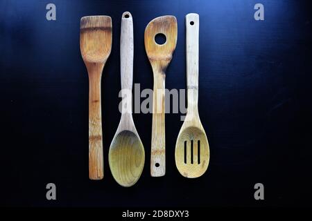 Alte Holzküche, Holzlöffel, Holzgabel, Spachtel und mehr auf schwarzem Hintergrund Stockfoto
