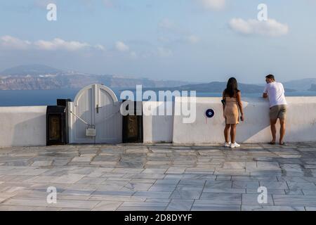 Oia, Santorini Island, Griechenland - 18. September 2020: Menschen auf der Terrasse mit Blick auf die Caldera. Weiße Wand. Stockfoto