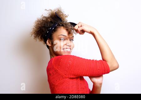 Seitenportrait einer lächelnden jungen Frau mit Haarbandana Biege ihren Bizepmuskel Stockfoto