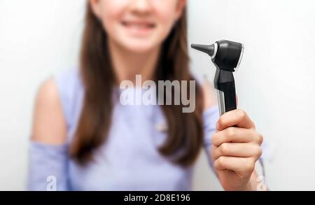 Otoscope in der Hand eines Teenagers, Nahaufnahme. Konzept Ohrbehandlung und Höruntersuchung für ein Kind. Weichfokus Stockfoto