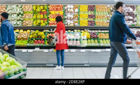 Im Supermarkt: Frau wählt Bio-Früchte in der Frischwarenabteilung des Stores. Sie holt Cantaloupe ab und legt sie in ihr Shopping Stockfoto