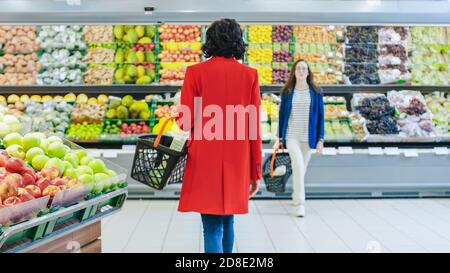 Im Supermarkt: Frau wählt Bio-Früchte in der Frischwarenabteilung des Stores. Sie holt Cantaloupe ab und legt sie in ihr Shopping Stockfoto