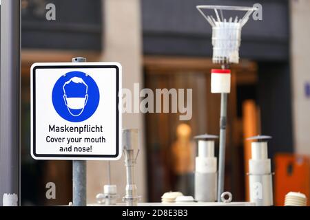 München, 26. Oktober 2020: Ein Schild mit einem Maskenpiktogramm und der Aufschrift "Maskenanforderung" befindet sich auf dem Max-Joseph-Platz in München, Bayern, Deutschland --- München, 26.10.2020: Ein Schild mit Masken-Piktogramm und der Aufschrift "Maskenpflicht" steht am Münchener Max-Joseph-Platz, München, Bayern, Deutschland Stockfoto