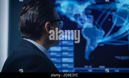 Portrait des Spezialagenten, der die Verantwortung für die Satellitenüberwachung von der Verfolgungsjagd ansieht. GPS-Tracking Fugitive in der Big Monitoring Stockfoto