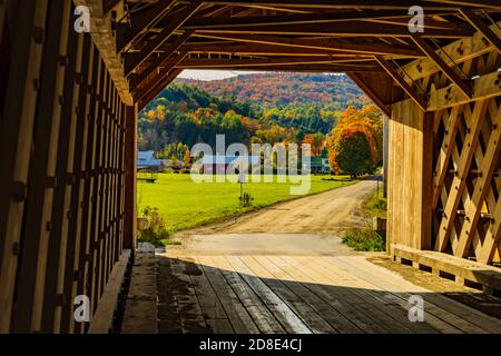 Blick aus dem Inneren eines historischen New England bedeckt Brücke auf einem Bauernhof und Hügel im Herbst bedeckt Laubfarbener Baum Stockfoto