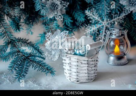 Glänzende Weihnachtsspielzeug mit Weihnachtsgeschenken. Korb, blaue Luftballons, Tannenzapfen, Boxen, Glassterne, Schneeflocken, Geschenkboxen auf dem Tisch. Stockfoto