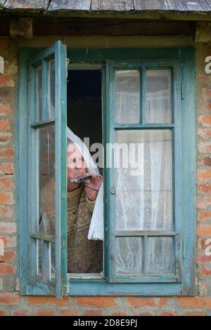 Miserable suchen älter männlich Vorhang twitcher Spionage auf Nachbarn aus Fenster, um jemanden zu finden, der die Regeln für die Sperrung einer Coronavirus-Pandemie bricht Stockfoto