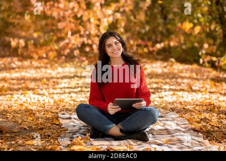 Wunderschöne junge Frau in rot gestrickt Pullover mit Tablet-Computer Im Herbstpark Stockfoto