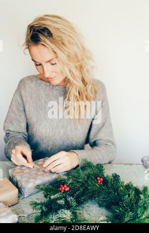 Frau macht weihnachtsgeschenk und Kranz Stockfoto