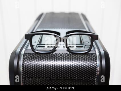 Eine Brille befindet sich auf dem schwarzen pc-Tower-Gehäuse mit usb-Anschlussbuchsen, Netz- und Reset-Tasten, Nahaufnahme Stockfoto