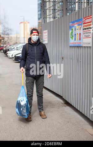 Erwachsene Mann, der Müll während der Coronavirus-Pandemie herausnimmt, ist es ohne Erlaubnis erlaubt. Beschriftung auf Platte in russischer Sprache: truschanlage A Stockfoto