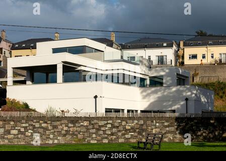 Neues modernes Haus mit großen Fenstern und klarem, zeitgenössischem Design gegenüber alten Reihenhäusern als Gegenüberstellung in Killarney, County Kerry, Irland Stockfoto